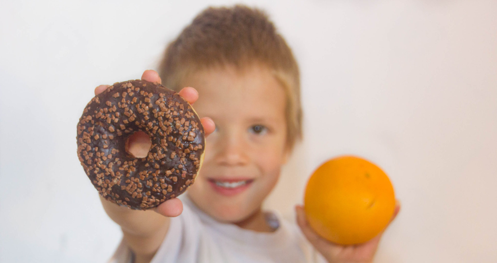 A child chooses a donut over an orange