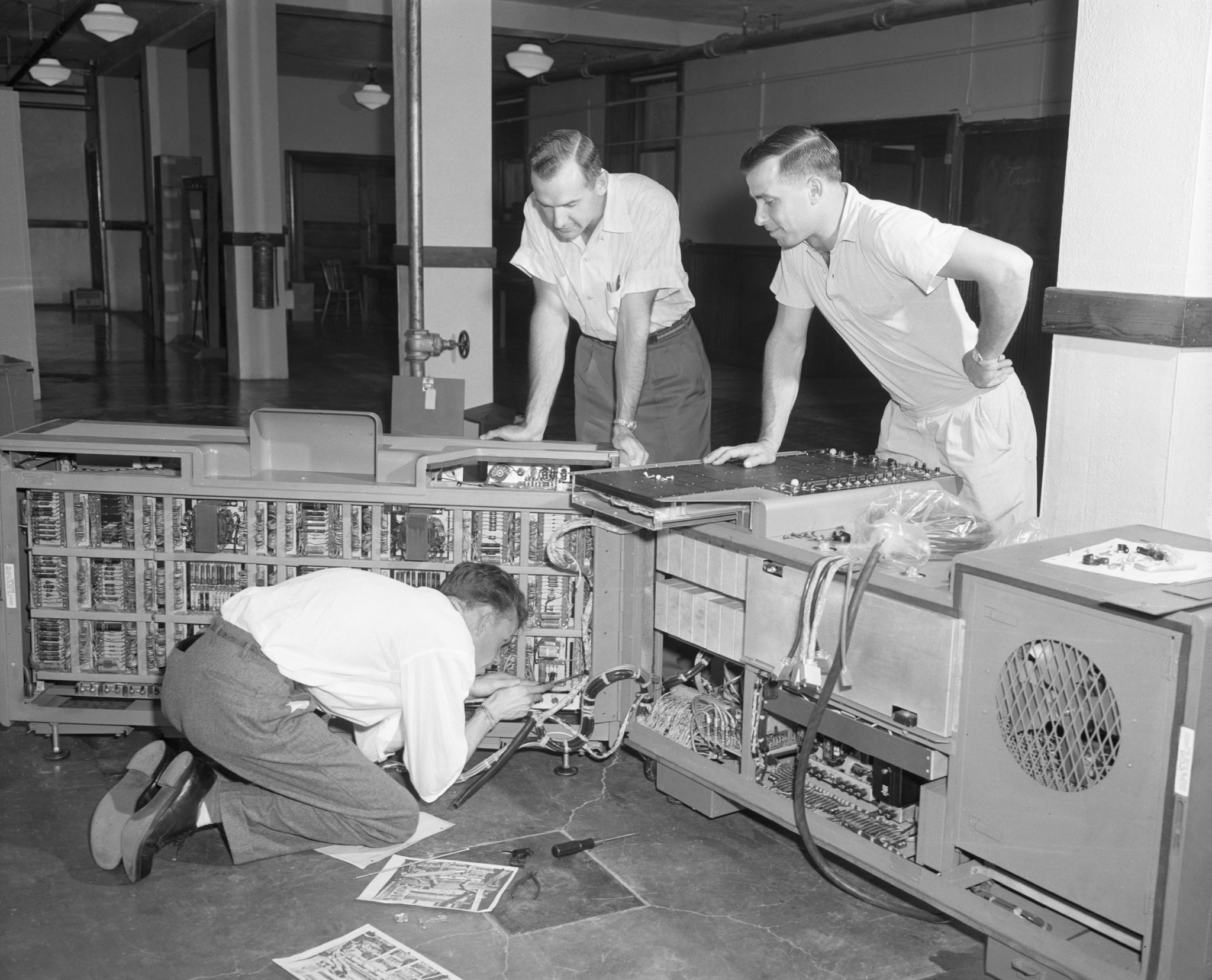 Photo of a new computing machine being installed in the basement of the Business Economy Building on July 10, 1958.  On the envelope are the names: Wayne Thomas, Engineer for Burroughs Corporation, Ken Whitcomb and Dr. Elmer Remmenga, but they don't specify which person is whichin the images.