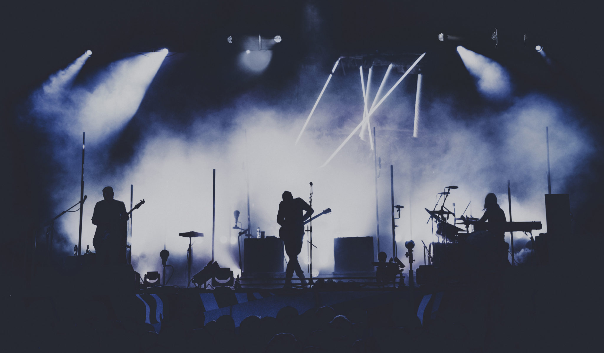 musicians perform on stage, silhouetted by stage lights