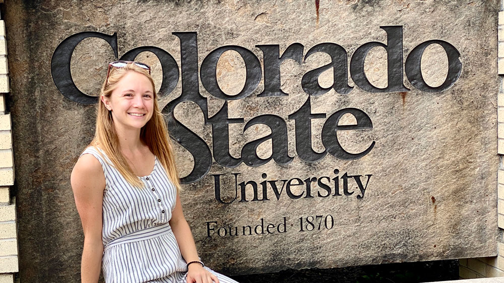 Addie Arnold sits in front of Colorado State University sign