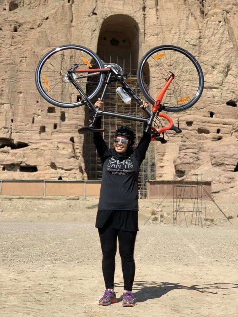 Zeinab Rezaie holds her bike above her head in celebration