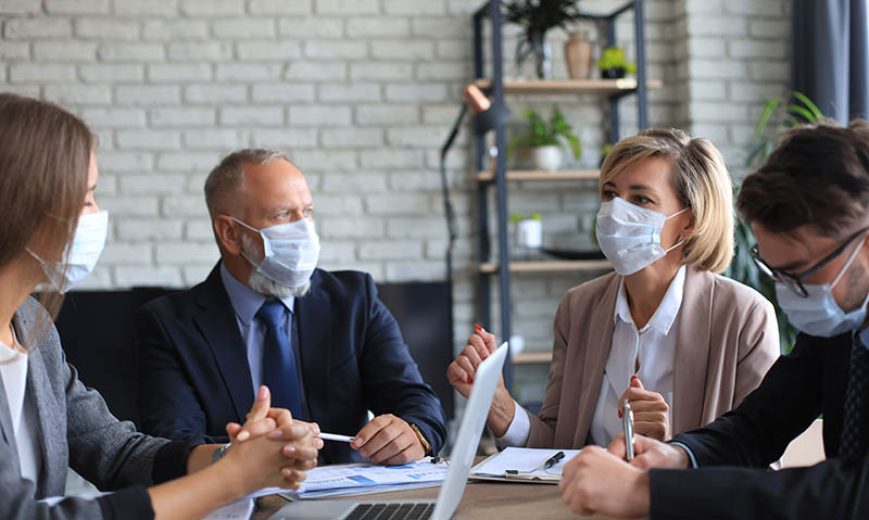 Business people wearing protective face masks while holding a presentation on a meeting during coronavirus epidemic